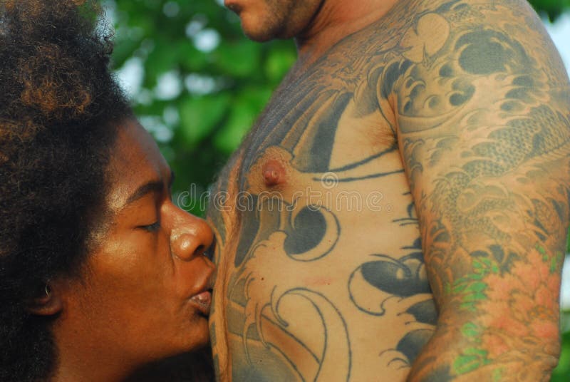 Pretty black woman kissing white man with traditional japanese tattoos. Pretty black woman kissing white man with traditional japanese tattoos.