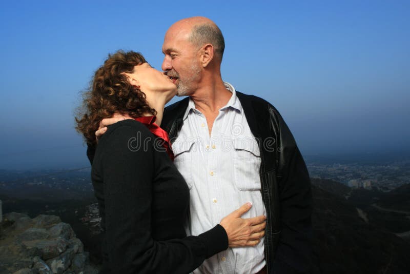 Mature couple locked in a deep, passionate kiss, full of longing