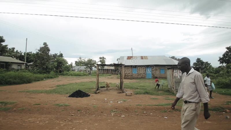 KISUMU KENJA, MAJ, - 15, 2018: Biedna Afrykańska wioska Ludzie angażują w ich dziennych sprawach dziecko niosą klingeryt
