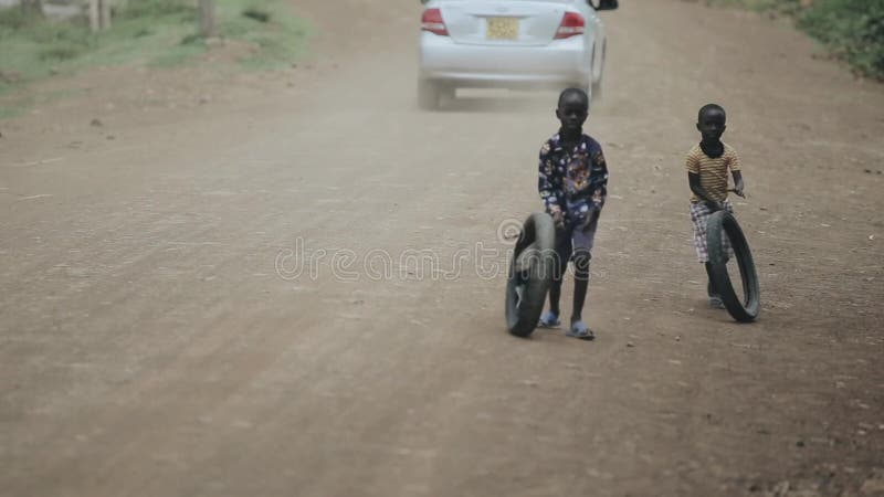 Kisumu Kenja, Maj, - 15, 2018: Dwa afrykańskiej chłopiec bawić się z oponami na drodze Dzieciaki ma zabawę wpólnie
