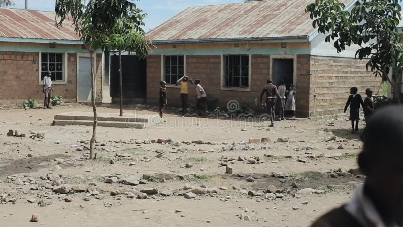 KISUMU KENJA, MAJ, - 15, 2018: Grupa Afrykańscy dzieci w mundurze bawić się futbol w szkolnym jardzie Biedna wioska wewnątrz