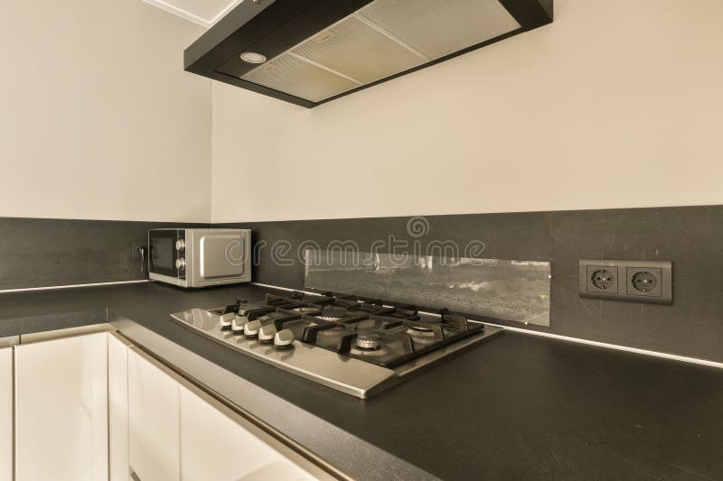 a kitchen with black and white tiles on the counter tops, stove hoods and range hood in the corner. a kitchen with black and white tiles on the counter tops, stove hoods and range hood in the corner