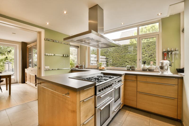 a modern kitchen with wood cabinets and stainless steel range hoods in the center of the room is an outdoor dining area. a modern kitchen with wood cabinets and stainless steel range hoods in the center of the room is an outdoor dining area