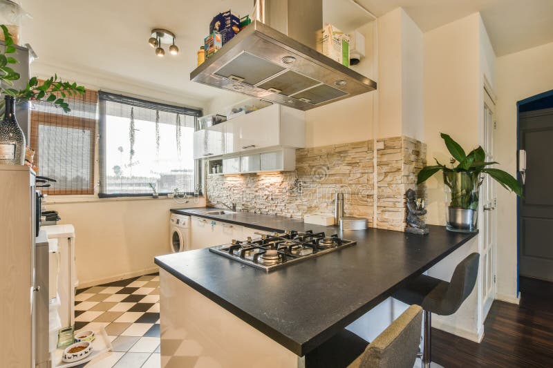 Amsterdam, Netherlands - 10 April, 2021: a kitchen with black and white tiles on the counter tops, stove hoods, and sink in it&#x27;s center. Amsterdam, Netherlands - 10 April, 2021: a kitchen with black and white tiles on the counter tops, stove hoods, and sink in it&#x27;s center