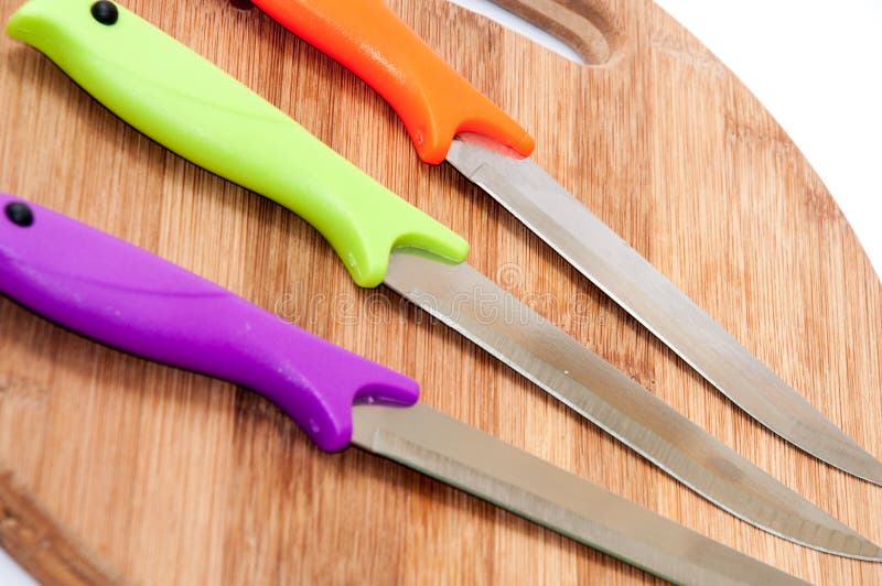 Kitchen Knives with Colorful Plastic Handles on a Wooden Board Stock
