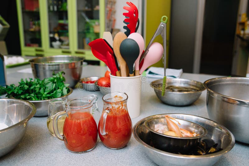 A busy kitchen scene featuring fresh tomato sauce, seafood, and various cooking utensils, ready for a delicious meal preparation. A busy kitchen scene featuring fresh tomato sauce, seafood, and various cooking utensils, ready for a delicious meal preparation