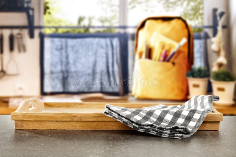 Kitchen table top with empty space for you products or decoration or kitchen accessories and yellow schoolbag and blurred window background with spring outside. Nice modern kitchen interior. Kitchen table top with empty space for you products or decoration or kitchen accessories and yellow schoolbag and blurred window background with spring outside. Nice modern kitchen interior.