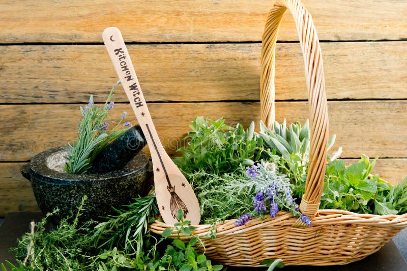 Kitchen Witch - wooden spoon, with fresh herbs and mortar and pestle against rustic background