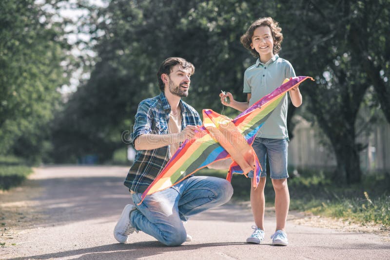 Dark-haired man holding a kite, his son looking excited royalty free stock photos