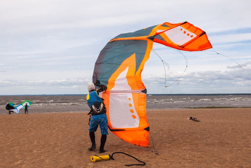 Kite Surfer Wearing a Wetsuit is Preparing His Kite on a Windy D Stock