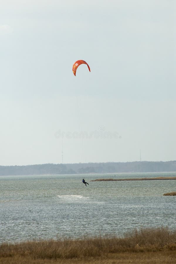 Kiteboarder surfe sur la baie de Sinepuxent outre de l'île d'Assateague, Maryl image stock Kiteboarder surfe sur la baie de Sinepuxent outre de l'île d'Assateague, Maryl image stock