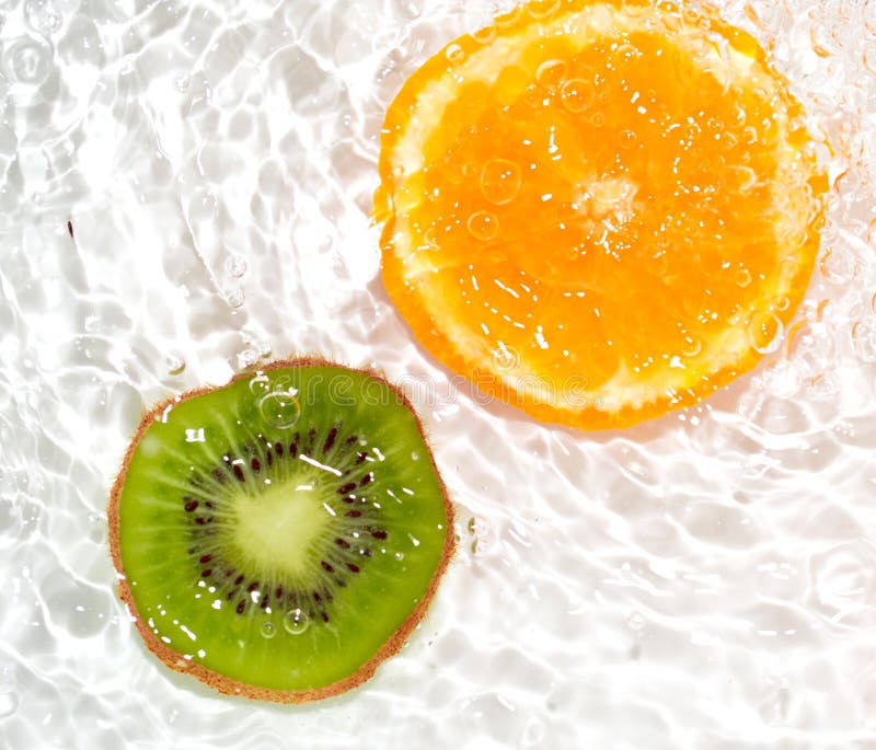 Kiwi et orange juteux dans l'eau sur un fond blanc Macro image stock Kiwi et orange juteux dans l'eau sur un fond blanc Macro image stock