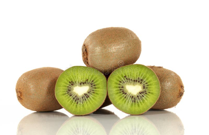 Two halves of a kiwi fruit resting white reflective surface with whole kiwi fruit behind on white background. Two halves of a kiwi fruit resting white reflective surface with whole kiwi fruit behind on white background