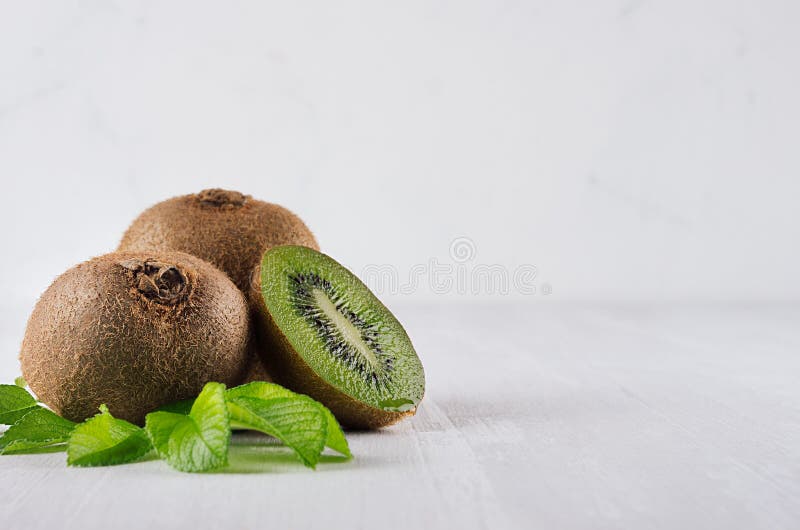 Kiwi verde copt, cu felie umedă, frunze tinere pe fond de lemn alb. hrană vegetativă sănătoasă. royalty free stock photography