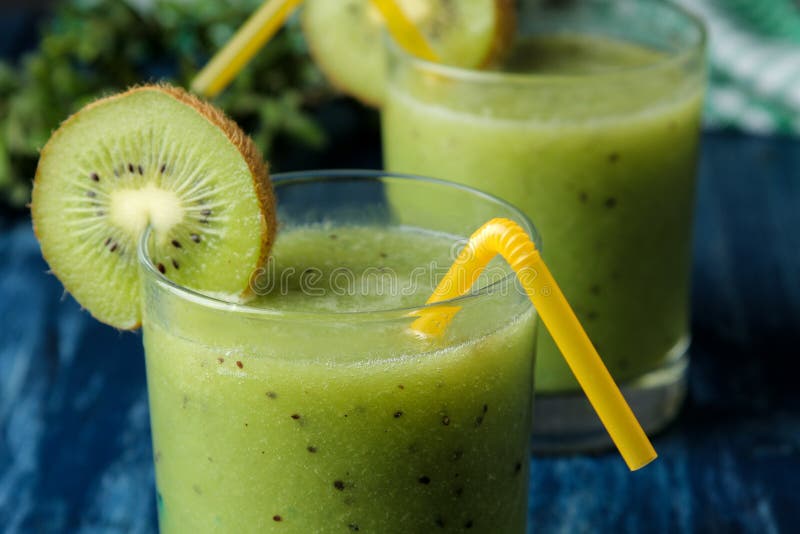 Kiwi Smoothies in a Glass Next To Fresh Kiwi Slices on a Blue Wooden ...