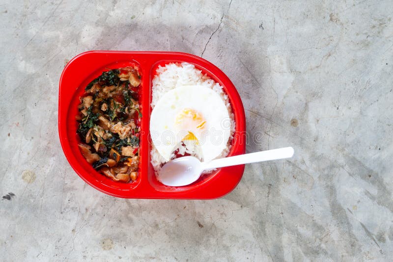 Klaar om kruidig Thais voedsel met rijst en gebraden ei in rode lunchdoos op concrete achtergrond te eten stock foto's Klaar om kruidig Thais voedsel met rijst en gebraden ei in rode lunchdoos op concrete achtergrond te eten stock foto's