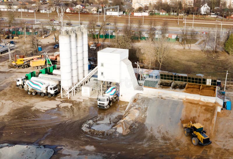 Ready mix concrete batching plant. Producing сoncrete and portland cement mortar for construction and formworks. Pouring concrete through to a ready-mixed truck. Drone view. Out of focus. Ready mix concrete batching plant. Producing сoncrete and portland cement mortar for construction and formworks. Pouring concrete through to a ready-mixed truck. Drone view. Out of focus