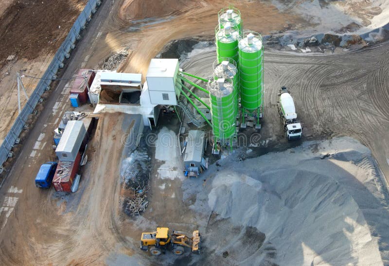 Ready mix concrete batching plant. Producing сoncrete and portland cement mortar for construction and formworks. Pouring concrete through to a ready-mixed truck. Drone view. Out of focus. Ready mix concrete batching plant. Producing сoncrete and portland cement mortar for construction and formworks. Pouring concrete through to a ready-mixed truck. Drone view. Out of focus