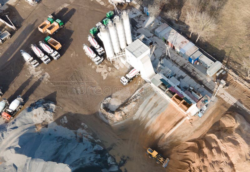 Ready mix concrete batching plant. Producing сoncrete and portland cement mortar for construction and formworks. Pouring concrete through to a ready-mixed truck. Drone view. Out of focus. Ready mix concrete batching plant. Producing сoncrete and portland cement mortar for construction and formworks. Pouring concrete through to a ready-mixed truck. Drone view. Out of focus