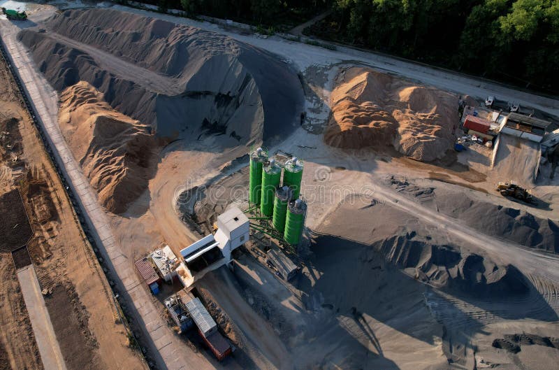 Ready mix concrete batching plant. Producing сoncrete and portland cement mortar for construction and formworks. Pouring concrete through to a ready-mixed truck. Drone view. Out of focus. Ready mix concrete batching plant. Producing сoncrete and portland cement mortar for construction and formworks. Pouring concrete through to a ready-mixed truck. Drone view. Out of focus