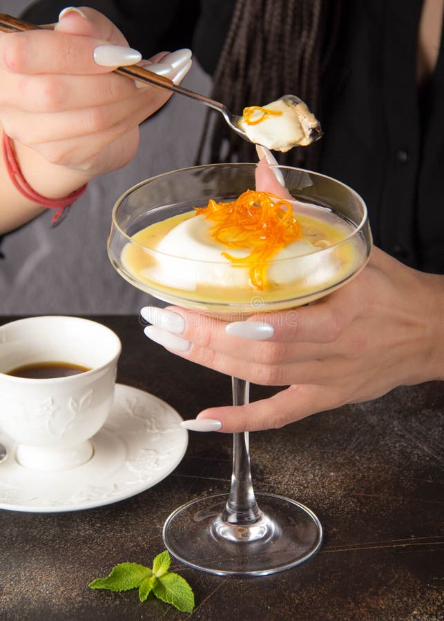 Klassischer Nachtisch Panna-Cotta im Glas mit orange Karamell und Kaffee, eine Frau isst mit Löffel lizenzfreie stockbilder Klassischer Nachtisch Panna-Cotta im Glas mit orange Karamell und Kaffee, eine Frau isst mit Löffel lizenzfreie stockbilder