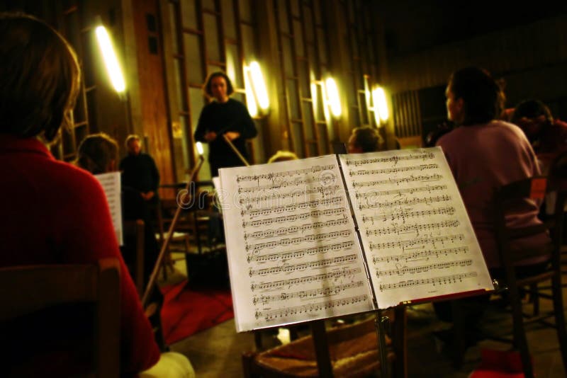 Classical music orchestra rehearsal with a music score on foreground. Classical music orchestra rehearsal with a music score on foreground.