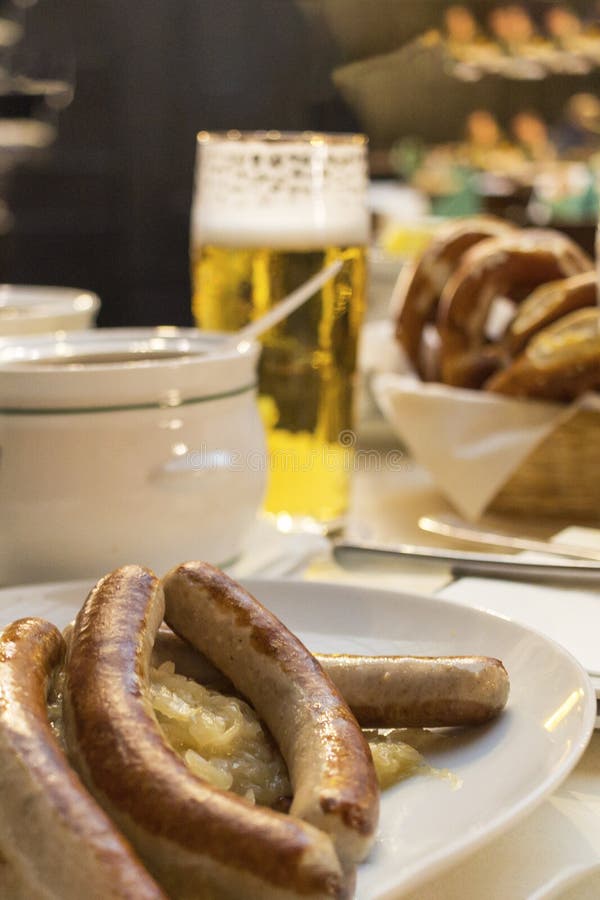 Klasyczny Niemiecki go?? restauracji sma? y? kie? basy z braised kapust? na wielkich biel talerzach z lekkim piwem, stoi na stole w zdjęcia stock