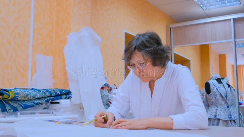 Kleermaker die met patroon van nieuwe kleermakerijeninzameling werken stock afbeelding Kleermaker die met patroon van nieuwe kleermakerijeninzameling werken stock afbeelding