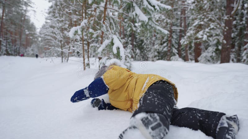 Klein kind slikt in de sneeuw en heeft plezier in het winterbos , gelukkig en zorgeloos kind