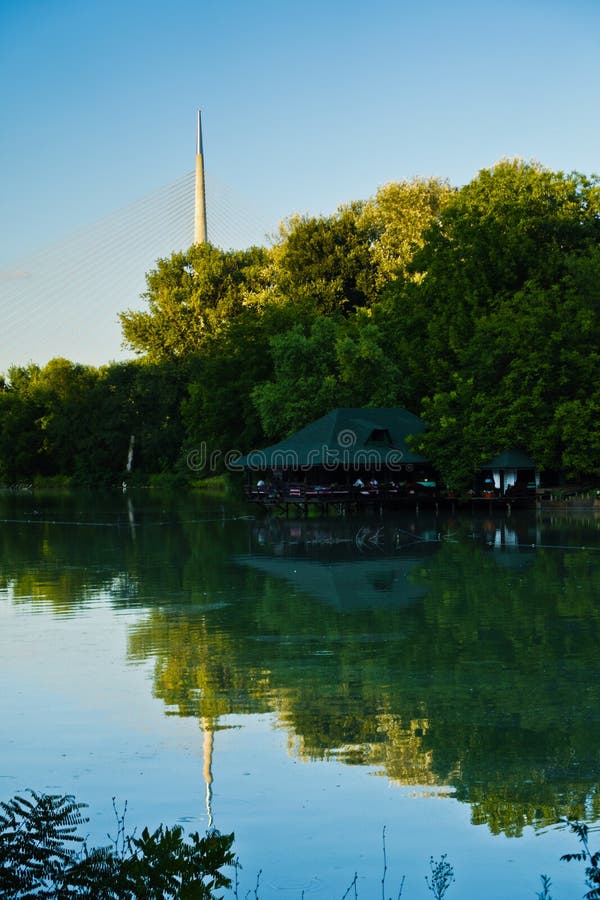 Klein meer met een houten cabine, Ada kabelbrug op een achtergrond, Belgrado royalty-vrije stock foto Klein meer met een houten cabine, Ada kabelbrug op een achtergrond, Belgrado royalty-vrije stock foto