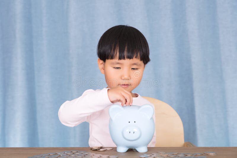 Klein meisje met munt in spaarpot stock foto's