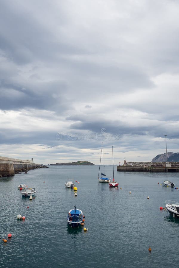 Kleine Boote am Eingang des Fischereihafens von Bermeo auf der Küste von Vizcaya an einem bewölkten Tag lizenzfreies stockfoto Kleine Boote am Eingang des Fischereihafens von Bermeo auf der Küste von Vizcaya an einem bewölkten Tag lizenzfreies stockfoto