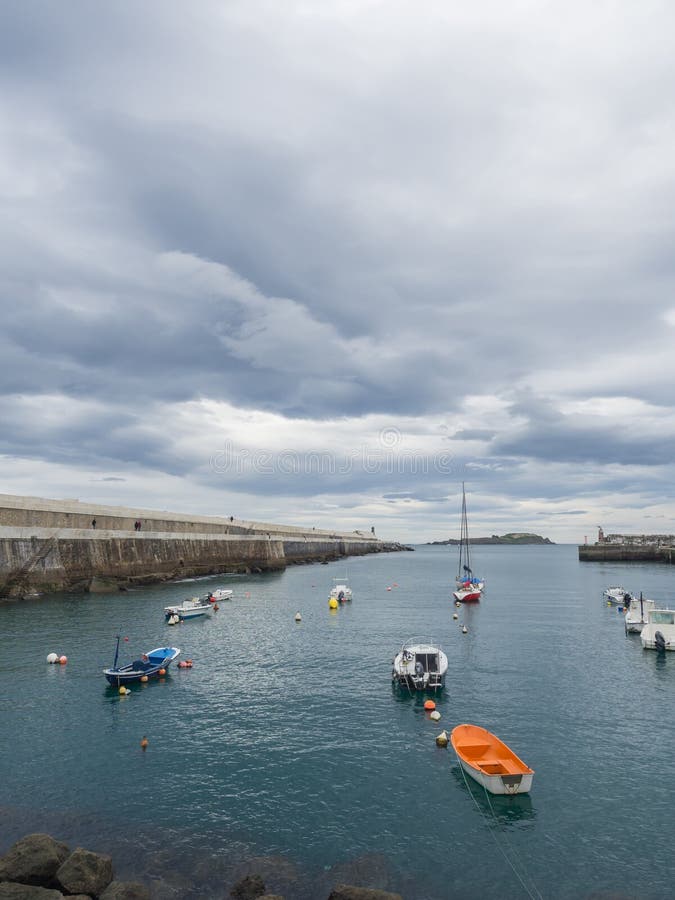 Kleine boten bij de ingang van de vissershaven van Bermeo op de kust van Biscaye op een bewolkte dag royalty-vrije stock foto Kleine boten bij de ingang van de vissershaven van Bermeo op de kust van Biscaye op een bewolkte dag royalty-vrije stock foto