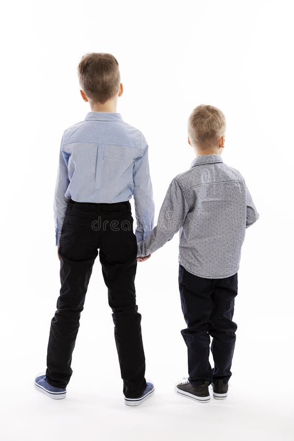 Kleine Brüder in blauen Hemden halten Händchen Rückansicht Weißer Hintergrund lizenzfreie stockfotografie Kleine Brüder in blauen Hemden halten Händchen Rückansicht Weißer Hintergrund lizenzfreie stockfotografie