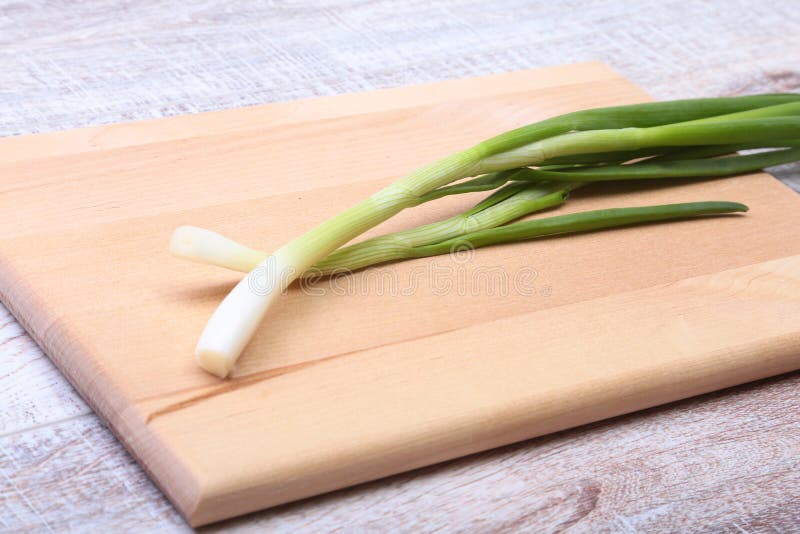 Kleine bundel van gewassen verse groene uien met lange stammen en uiterst kleine wortels op houten lijst stock foto's Kleine bundel van gewassen verse groene uien met lange stammen en uiterst kleine wortels op houten lijst stock foto's