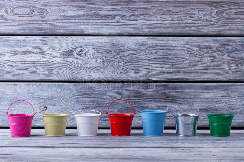 Kleine decoratieve emmers op grijze houten achtergrond stock afbeelding Kleine decoratieve emmers op grijze houten achtergrond stock afbeelding