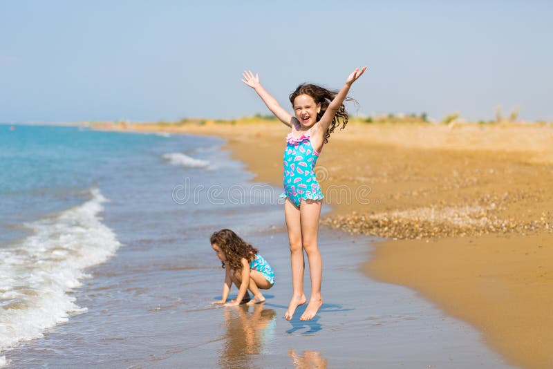 Kleine gelukkige meisjes in helder zwempakkenspel op het strand Kinderen op vakantie De vakantie van de familie Gelukkige zusters stock afbeelding Kleine gelukkige meisjes in helder zwempakkenspel op het strand Kinderen op vakantie De vakantie van de familie Gelukkige zusters stock afbeelding