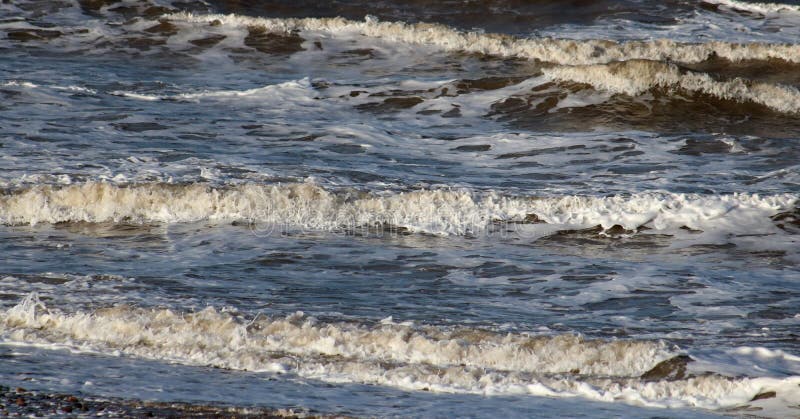 Kleine golven die aan wal op strand in Fleetwood komen stock fotografie Kleine golven die aan wal op strand in Fleetwood komen stock fotografie
