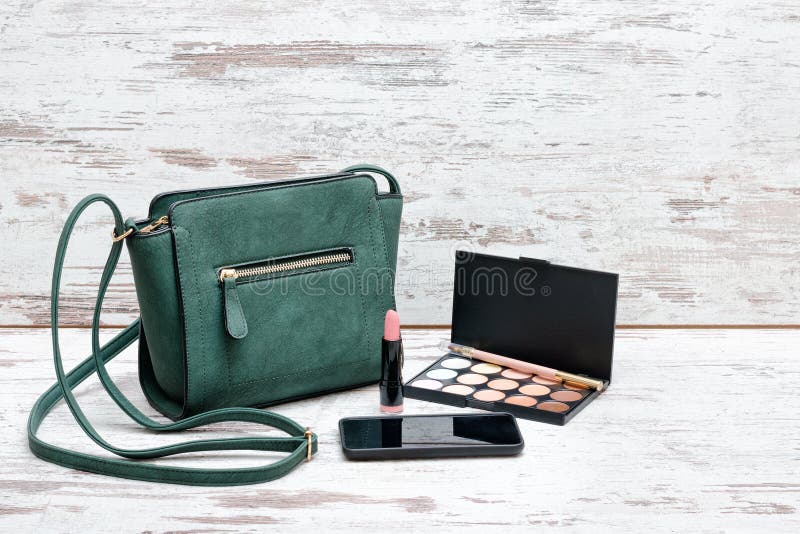Kleine grüne Damen Handtasche, Lidschattenpalette, Lippenstift und Inspektion stockfotografie Kleine grüne Damen Handtasche, Lidschattenpalette, Lippenstift und Inspektion stockfotografie