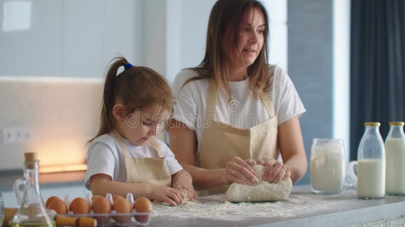 Kleine Helfertochter hilft ihrer Mutter, hausgemachten Teig in der Küche zuzubereiten stock video footage