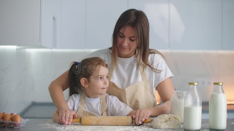 Kleine Helfertochter hilft ihrer Mutter, hausgemachten Teig in der Küche zuzubereiten stock video
