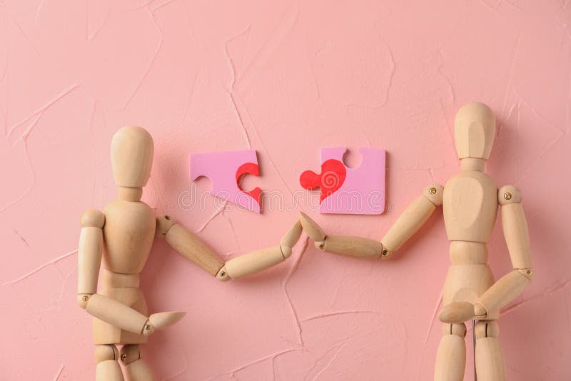 Kleine hölzerne Mannequins mit rosa Puzzlespielen auf Farbhintergrund lizenzfreie stockbilder Kleine hölzerne Mannequins mit rosa Puzzlespielen auf Farbhintergrund lizenzfreie stockbilder