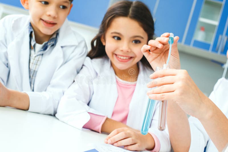 Kleine jonge geitjes met leraar die in schoollaboratorium vloeistoffenclose-up mengen royalty-vrije stock foto's Kleine jonge geitjes met leraar die in schoollaboratorium vloeistoffenclose-up mengen royalty-vrije stock foto's