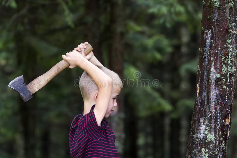 Kleine jongen met zware oude scherpe de boomtroef van de ijzerbijl in bos op de zomerdag Openluchtactiviteiten en fysieke arbeid royalty-vrije stock afbeeldingen Kleine jongen met zware oude scherpe de boomtroef van de ijzerbijl in bos op de zomerdag Openluchtactiviteiten en fysieke arbeid royalty-vrije stock afbeeldingen
