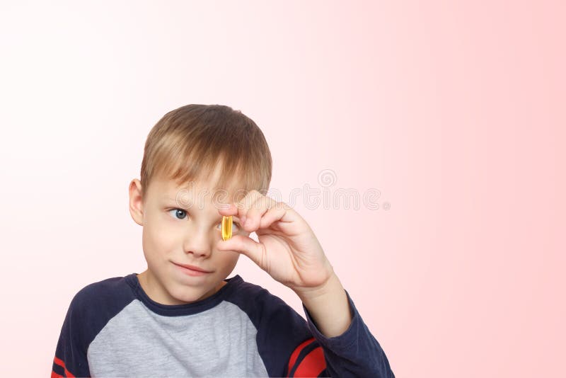 Kleine jongen neemt visolie op Vitaminen D, E Het kind dat omega-3 capsule tussen zijn vingers houdt Gezonde voeding Snijden kopi royalty-vrije stock foto's Kleine jongen neemt visolie op Vitaminen D, E Het kind dat omega-3 capsule tussen zijn vingers houdt Gezonde voeding Snijden kopi royalty-vrije stock foto's