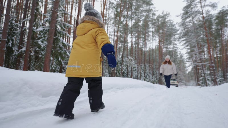 Kleine jongen rent naar moeder in sneeuwwinterbos - gelukkige ontmoeting tussen kind en moeder