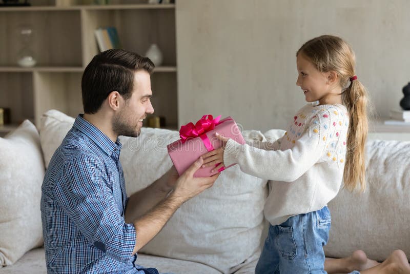 Kleine Kind Tochter, die Geschenkschachtel für jungen Vater schenkt. lizenzfreies stockbild
