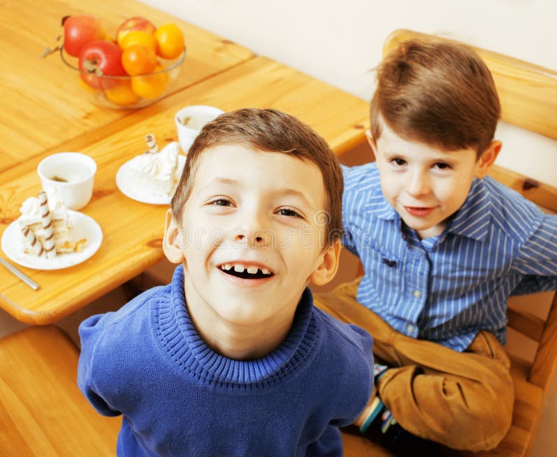 Kleine leuke jongens die dessert op houten keuken eten Het binnenland van het huis stock foto's Kleine leuke jongens die dessert op houten keuken eten Het binnenland van het huis stock foto's