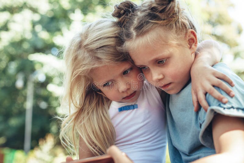 Kleine meisjes die mobiel met aandacht bekijken stock afbeelding Kleine meisjes die mobiel met aandacht bekijken stock afbeelding