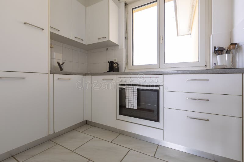 Small modern white kitchen with oven, coffee maker and stove with large bright window with a view. Nobody inside. Small modern white kitchen with oven, coffee maker and stove with large bright window with a view. Nobody inside